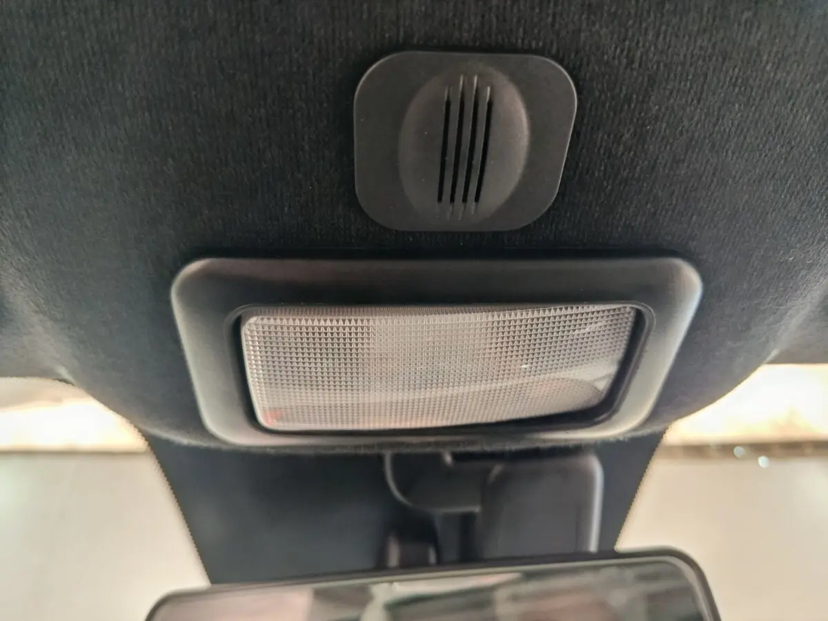 Plafonnier intérieur noir avec haut-parleur intégré, au-dessus du rétroviseur dans une Fiat 500 bleue hybride.