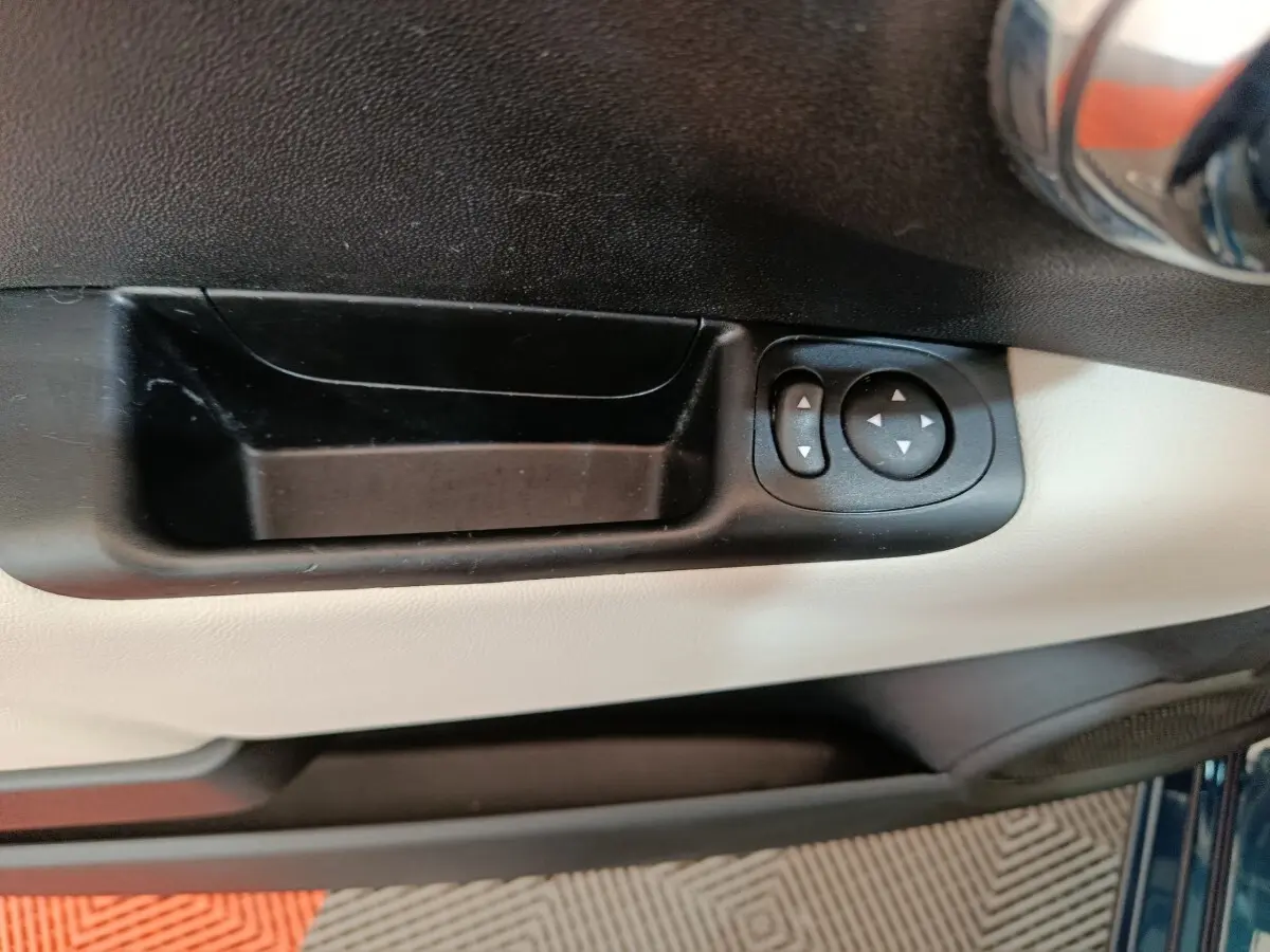 Gros plan sur la commande de réglage des rétroviseurs côté conducteur, intérieur bicolore noir et beige du FIAT 500 bleu.