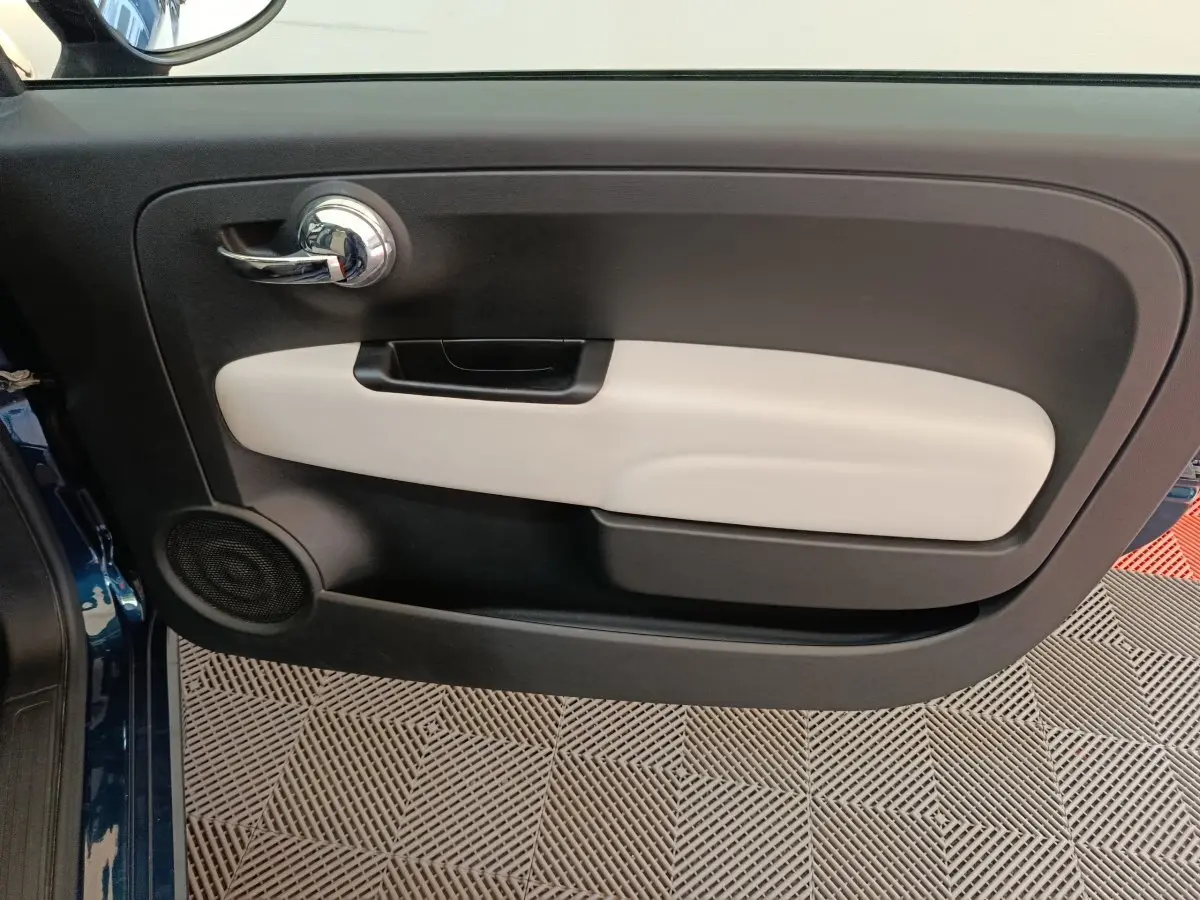 Vue rapprochée de la porte avant gauche bleu de la FIAT 500 Dolcevita avec insert beige et poignée chromée.
