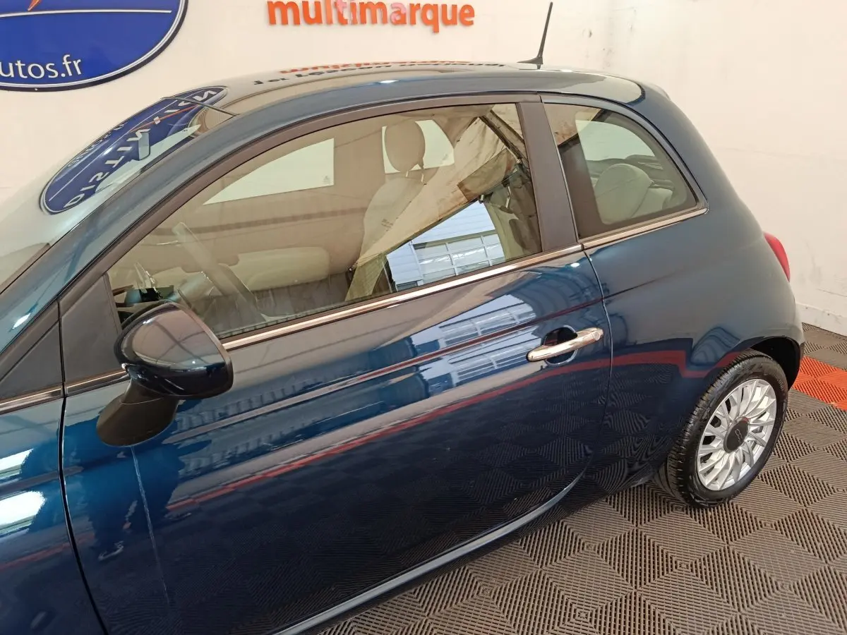 Vue latérale droite d'une FIAT 500 Dolcevita hybride bleu métallisé, avec jantes alliage et rétroviseur assorti.