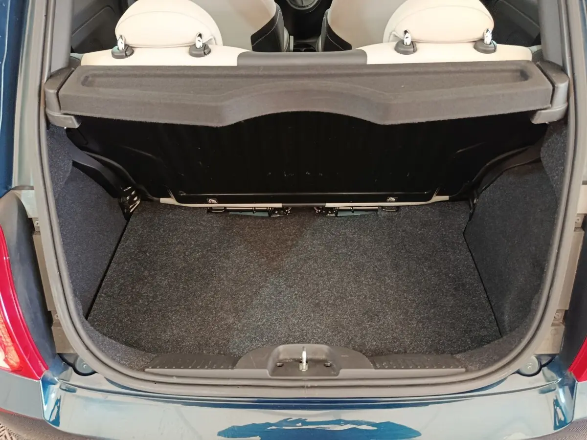 Coffre ouvert vu de dessus d'une FIAT 500 Dolcevita bleu, montrant la banquette arrière beige et le tapis de coffre.