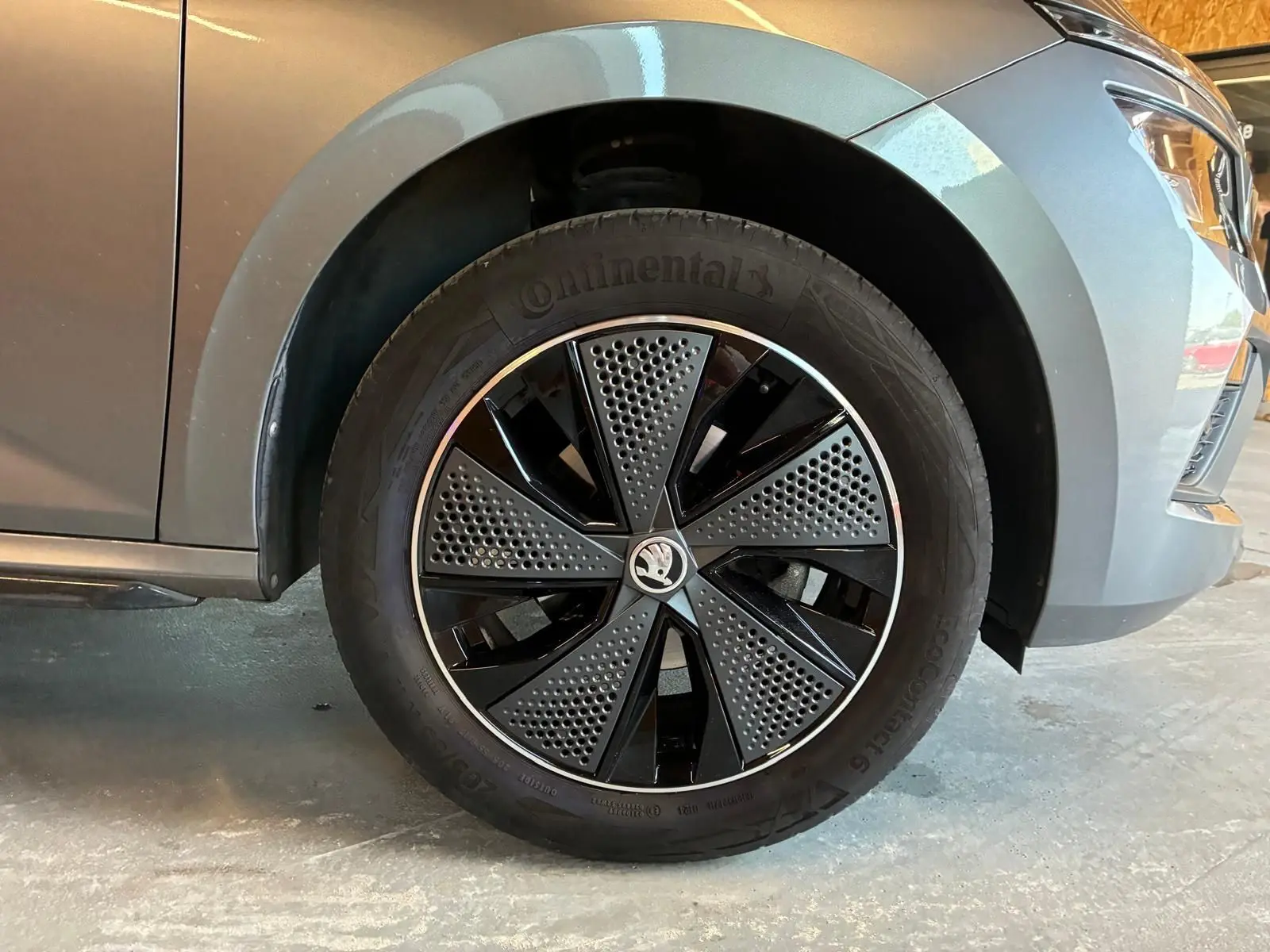 Gros plan sur la roue avant gauche d’un Skoda Kamiq gris foncé 2024 avec jante noire et grise au design moderne.