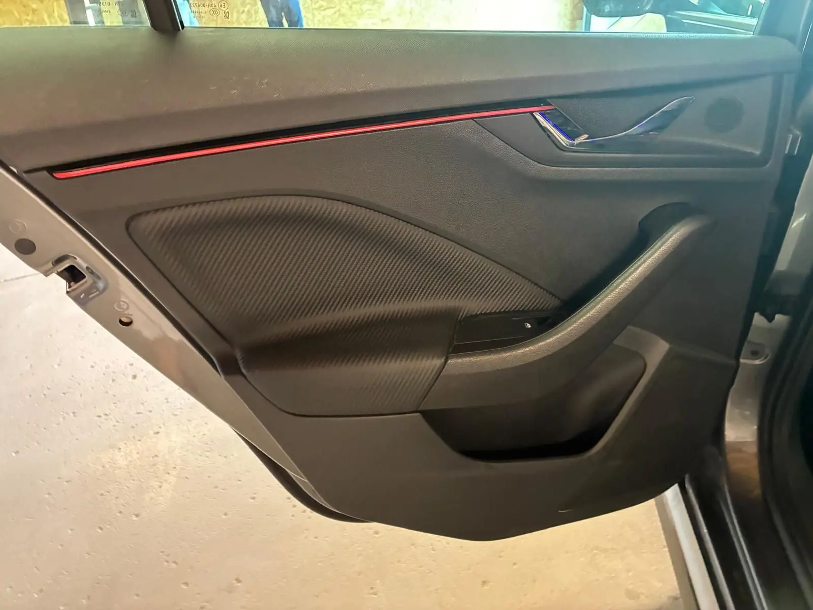 Vue intérieure de la porte avant gauche du Skoda Kamiq 2024 gris foncé, avec insert décoratif rouge et finition noire.