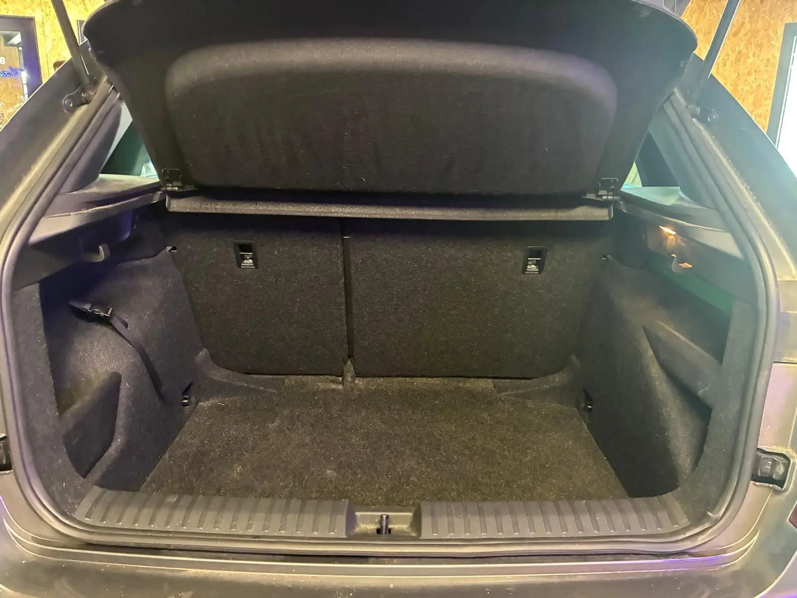 Coffre ouvert vu de l'arrière d'un Skoda Kamiq gris foncé 2024, montrant un espace de chargement vide et propre.