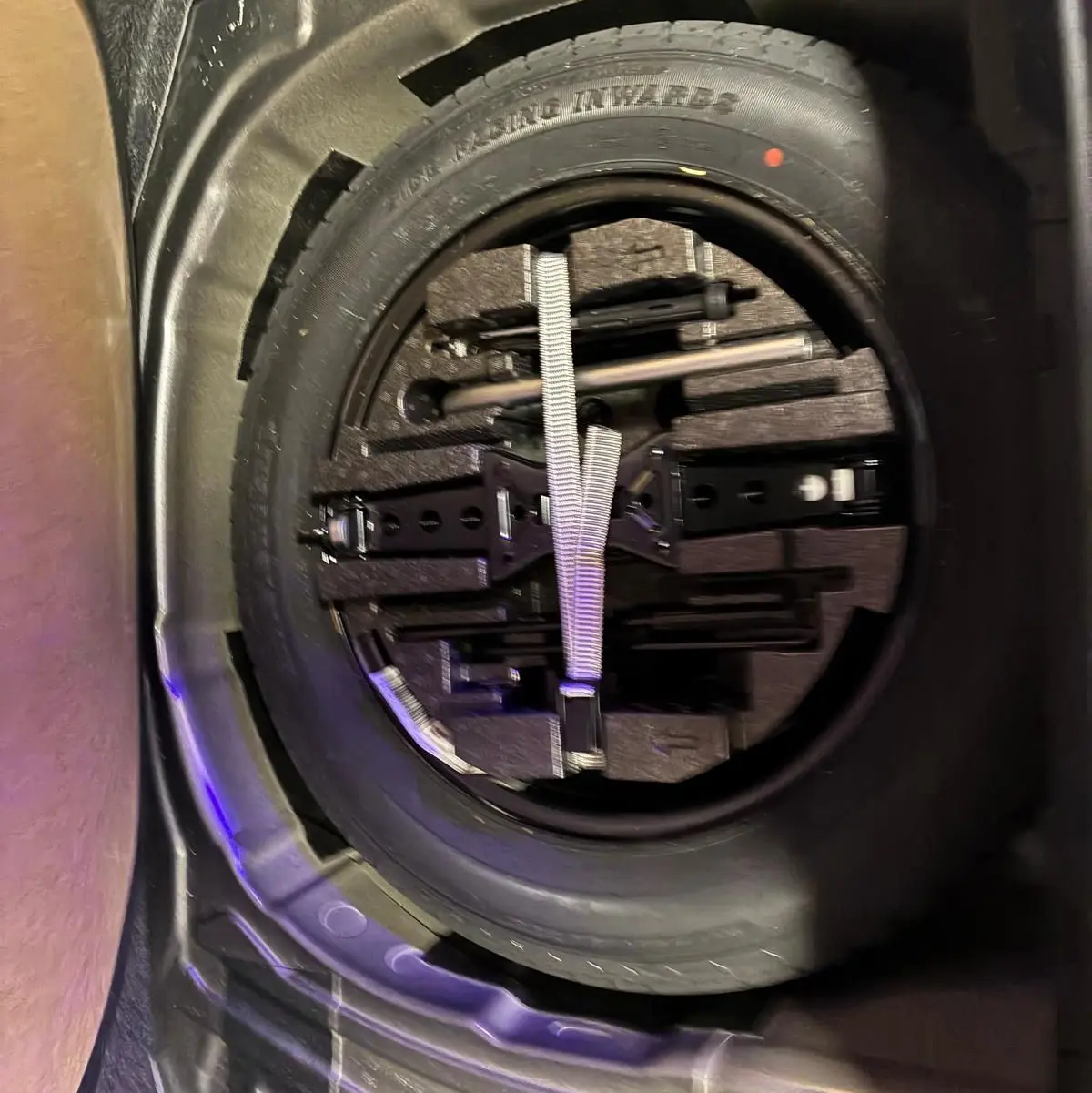 Vue rapprochée de la roue de secours et des outils de bord dans le coffre d'un Skoda Kamiq gris foncé 2024.