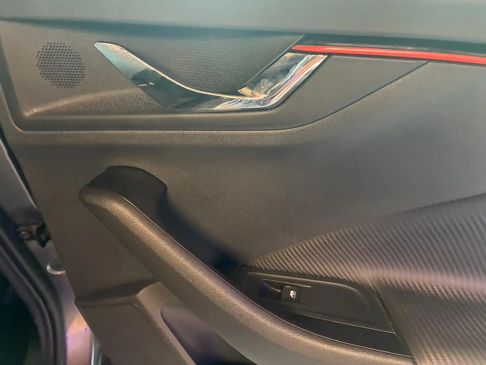 Détail de la porte intérieure côté conducteur du Skoda Kamiq 2024 gris foncé, avec poignée chromée et bouton de verrouillage.