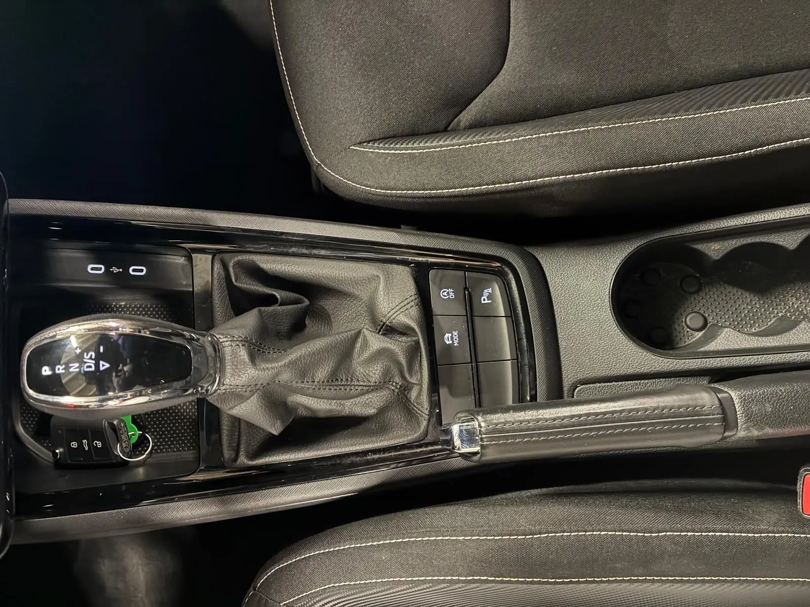 Vue plongeante sur la console centrale noire du Skoda Kamiq 2024, avec levier de vitesse automatique et frein à main cuir.