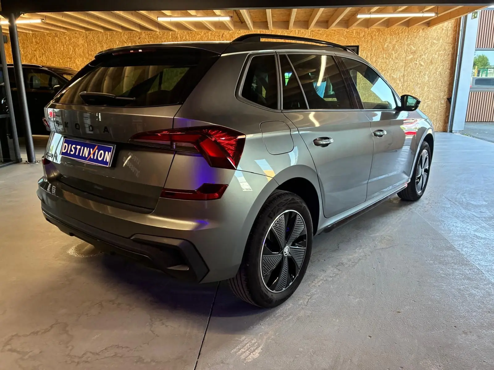 Vue 3/4 arrière droite du Skoda Kamiq gris foncé 2024 avec jantes noires et feux arrière LED distinctifs.