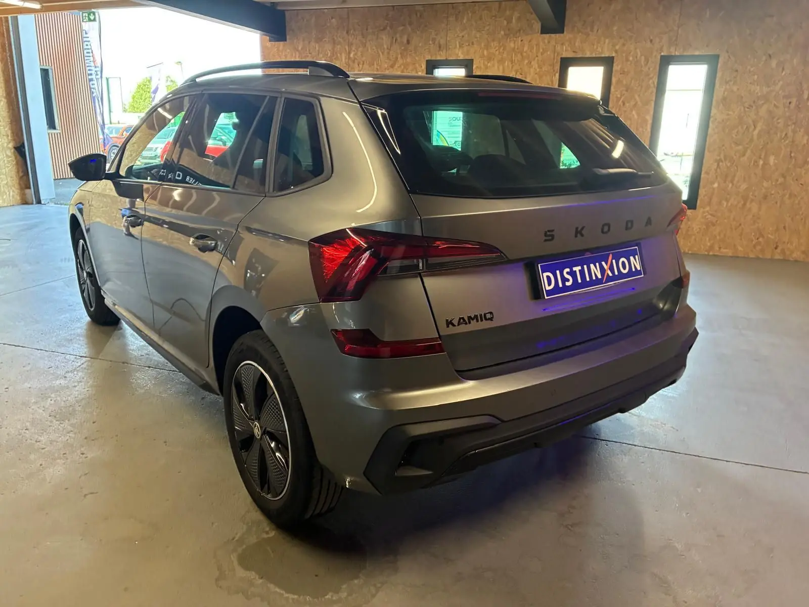 Vue 3/4 arrière droite d'un Skoda Kamiq gris foncé 2024, finition Monte-Carlo avec feux arrière LED et jantes spécifiques.