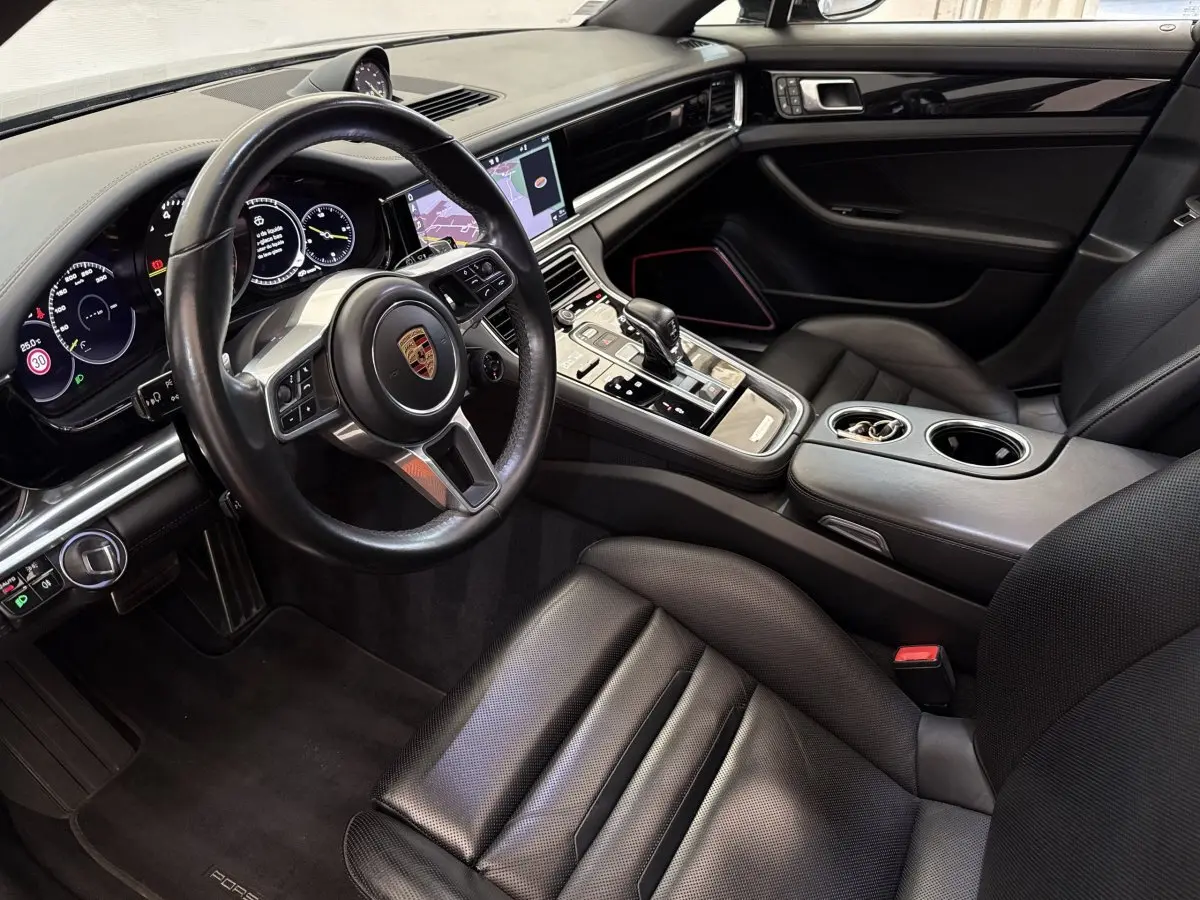 Intérieur noir de la Porsche Panamera 4 E-Hybrid Sport Turismo 2018, vue côté conducteur avec volant cuir multifonctions et écran tactile.