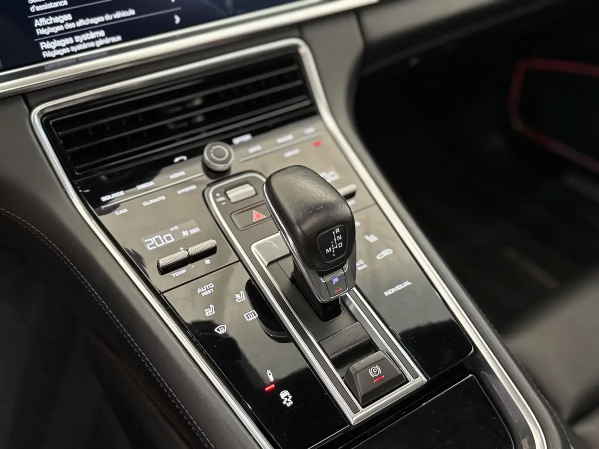 Gros plan sur la console centrale noire de la Porsche Panamera 4 E-Hybrid Sport Turismo avec levier de vitesse et commandes tactiles.