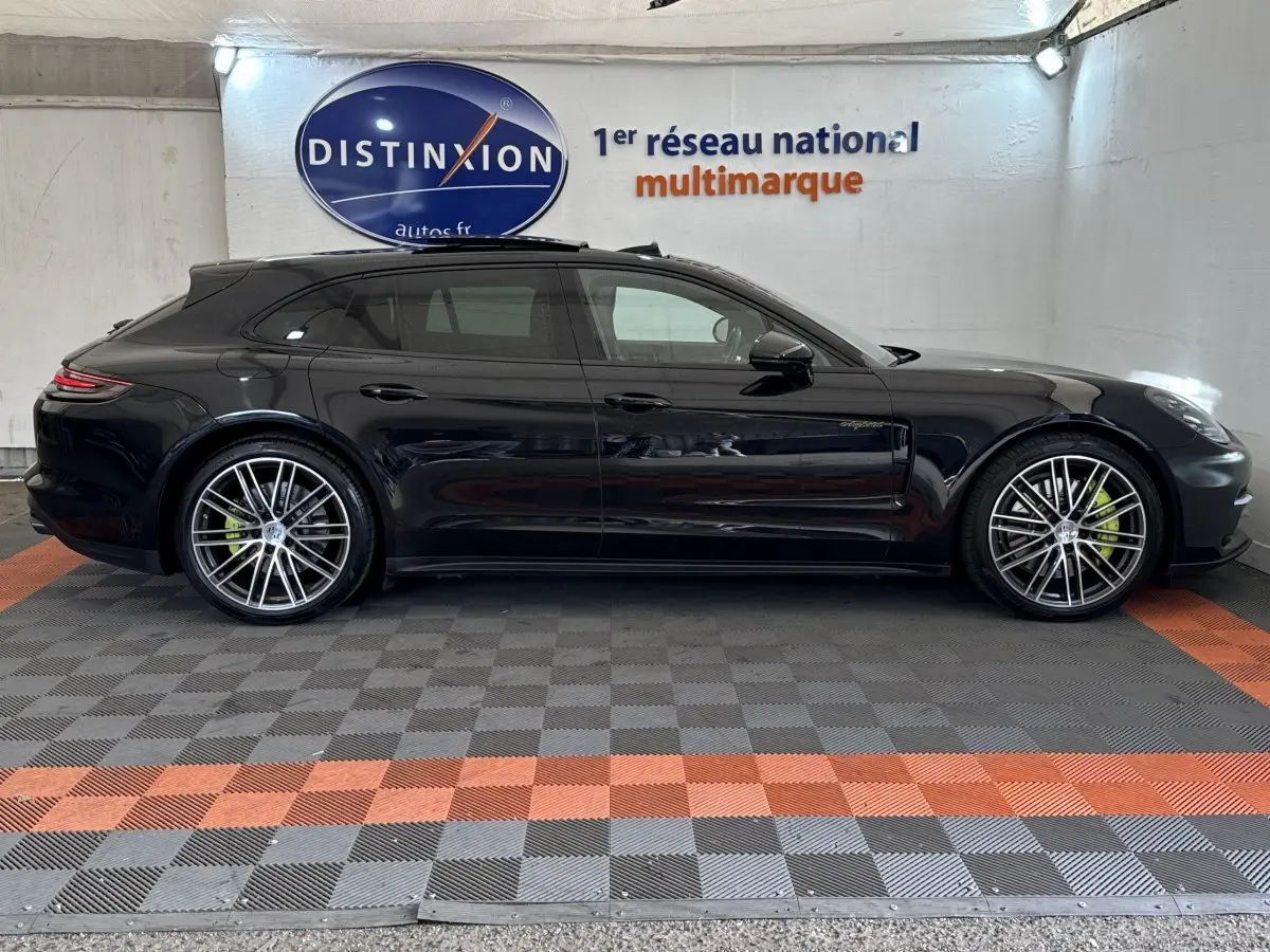 Vue latérale droite d'une Porsche Panamera 4 E-Hybrid Sport Turismo noire avec jantes alliage et étriers de frein verts.
