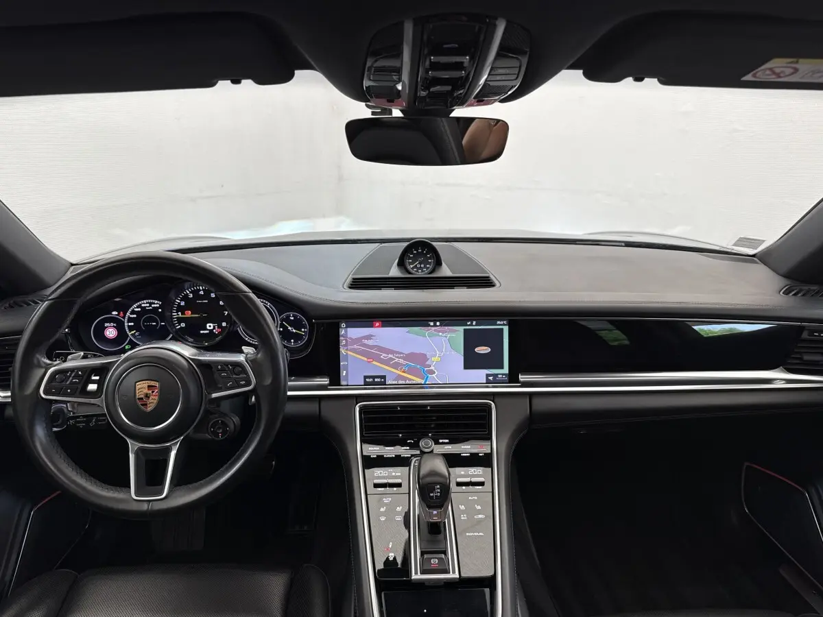 Vue intérieure avant du tableau de bord noir de la Porsche Panamera 4 E-Hybrid Sport Turismo avec écran tactile de navigation.