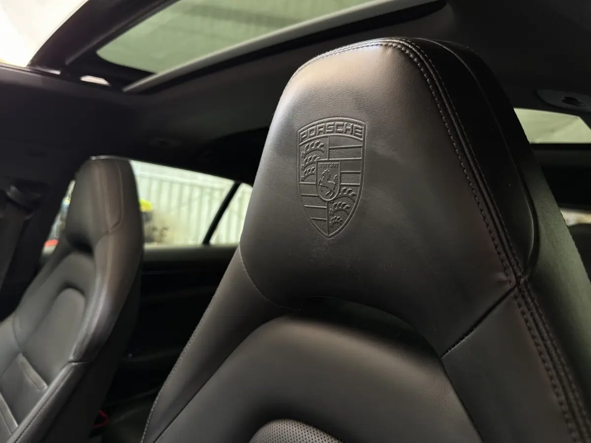 Gros plan sur l'appui-tête en cuir noir embossé du logo Porsche à l'avant intérieur d'une Panamera 4 E-Hybrid Sport Turismo.