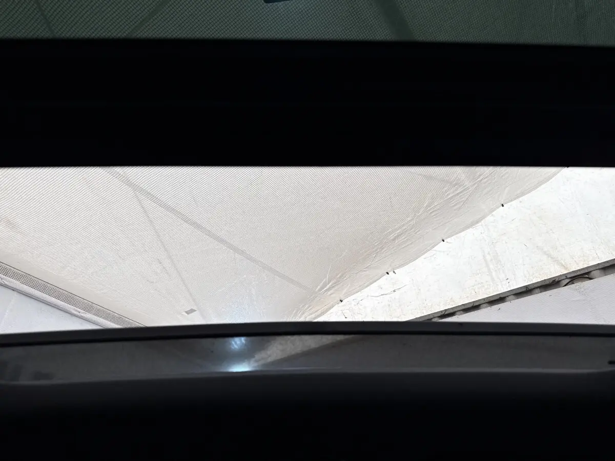 Vue partielle du toit ouvrant panoramique de la Porsche Panamera 4 E-Hybrid Sport Turismo noir, intérieur sombre.