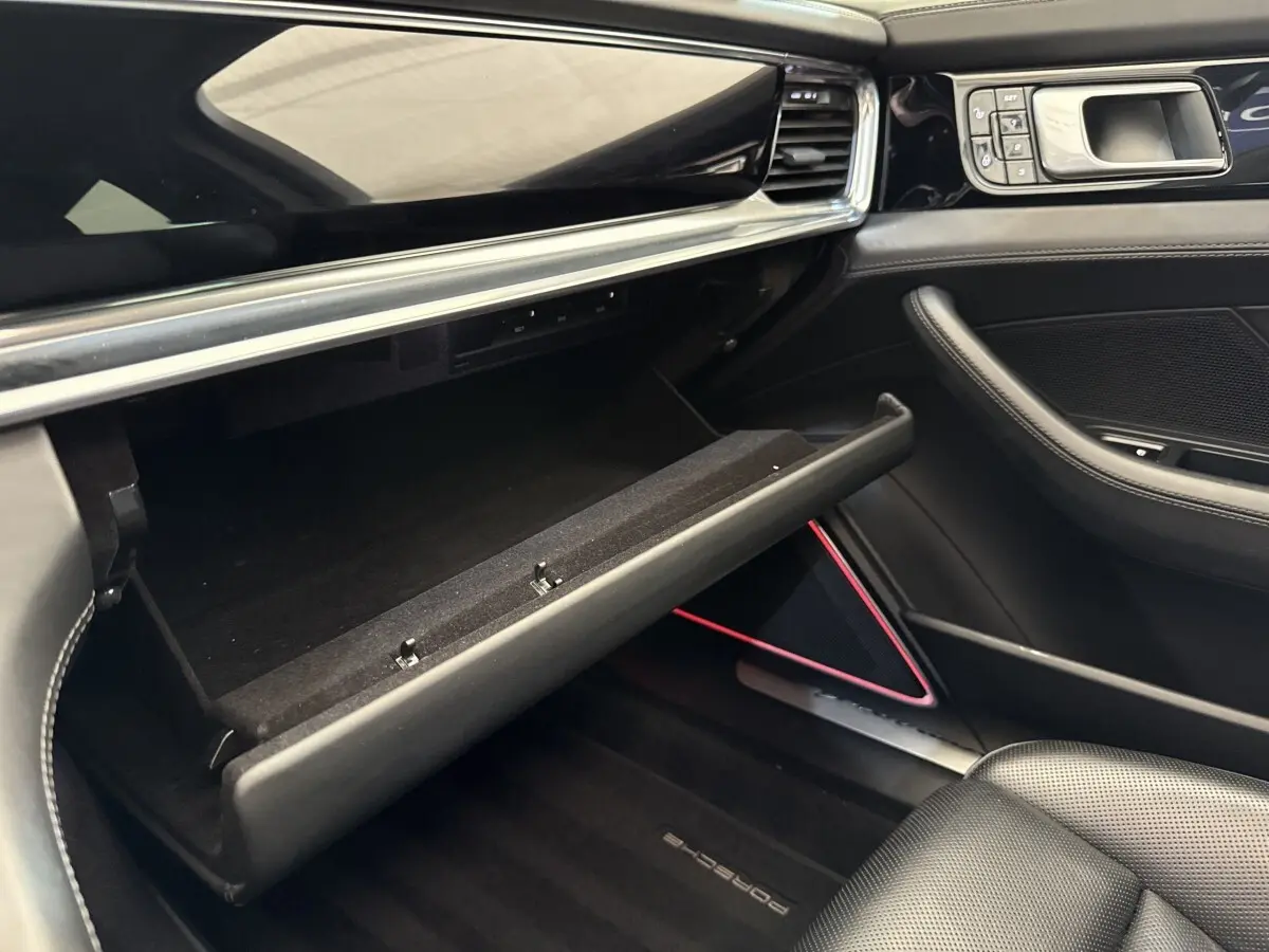 Vue intérieure côté passager de la Porsche Panamera 4 E-Hybrid Sport Turismo 2018, boîte à gants ouverte, garnitures noires élégantes.