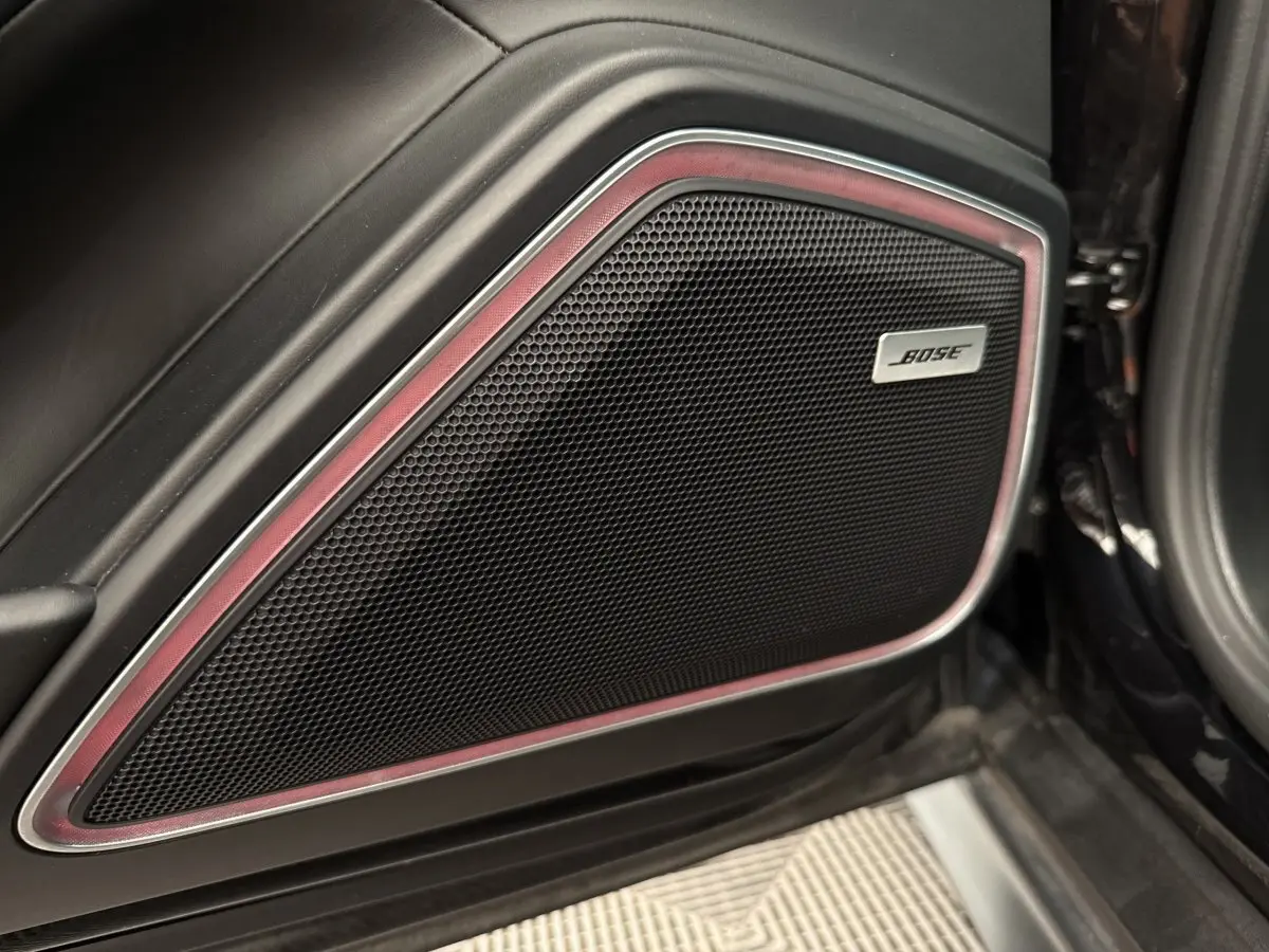 Gros plan sur le haut-parleur Bose intégré dans la porte intérieure côté conducteur d'une Porsche Panamera 4 E-Hybrid Sport Turismo noire.