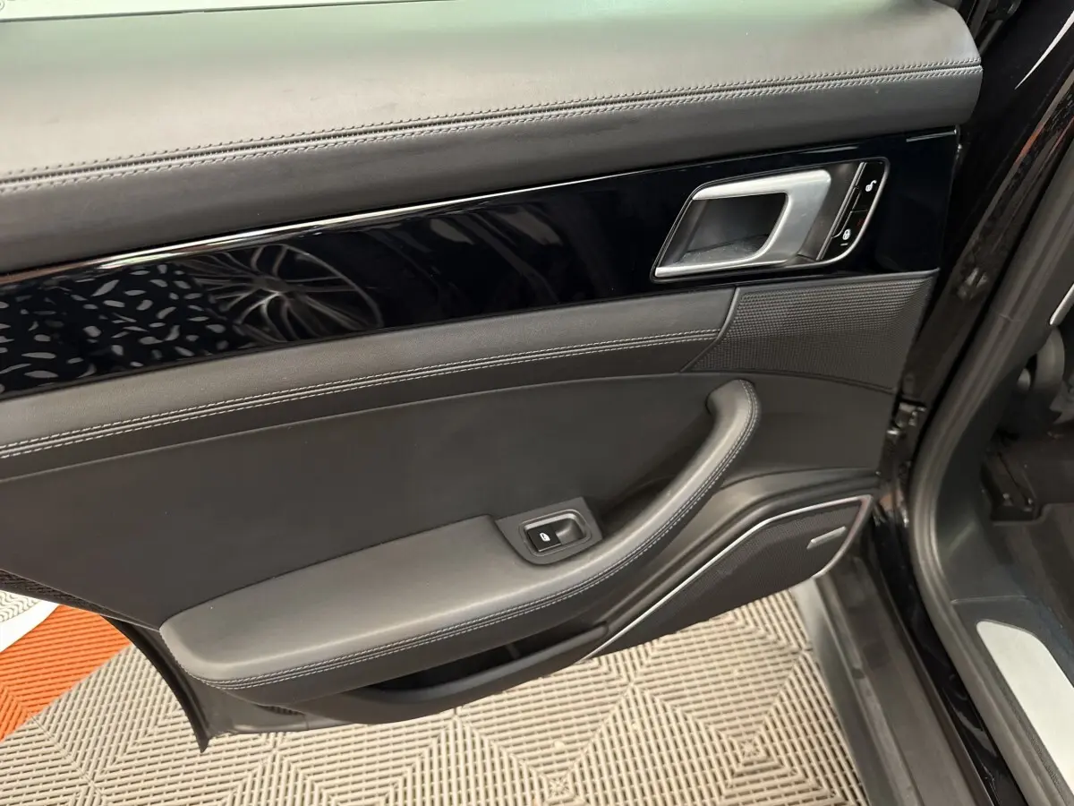 Vue intérieure de la porte avant gauche noire de la Porsche Panamera 4 E-Hybrid Sport Turismo avec garniture cuir et poignée argentée.