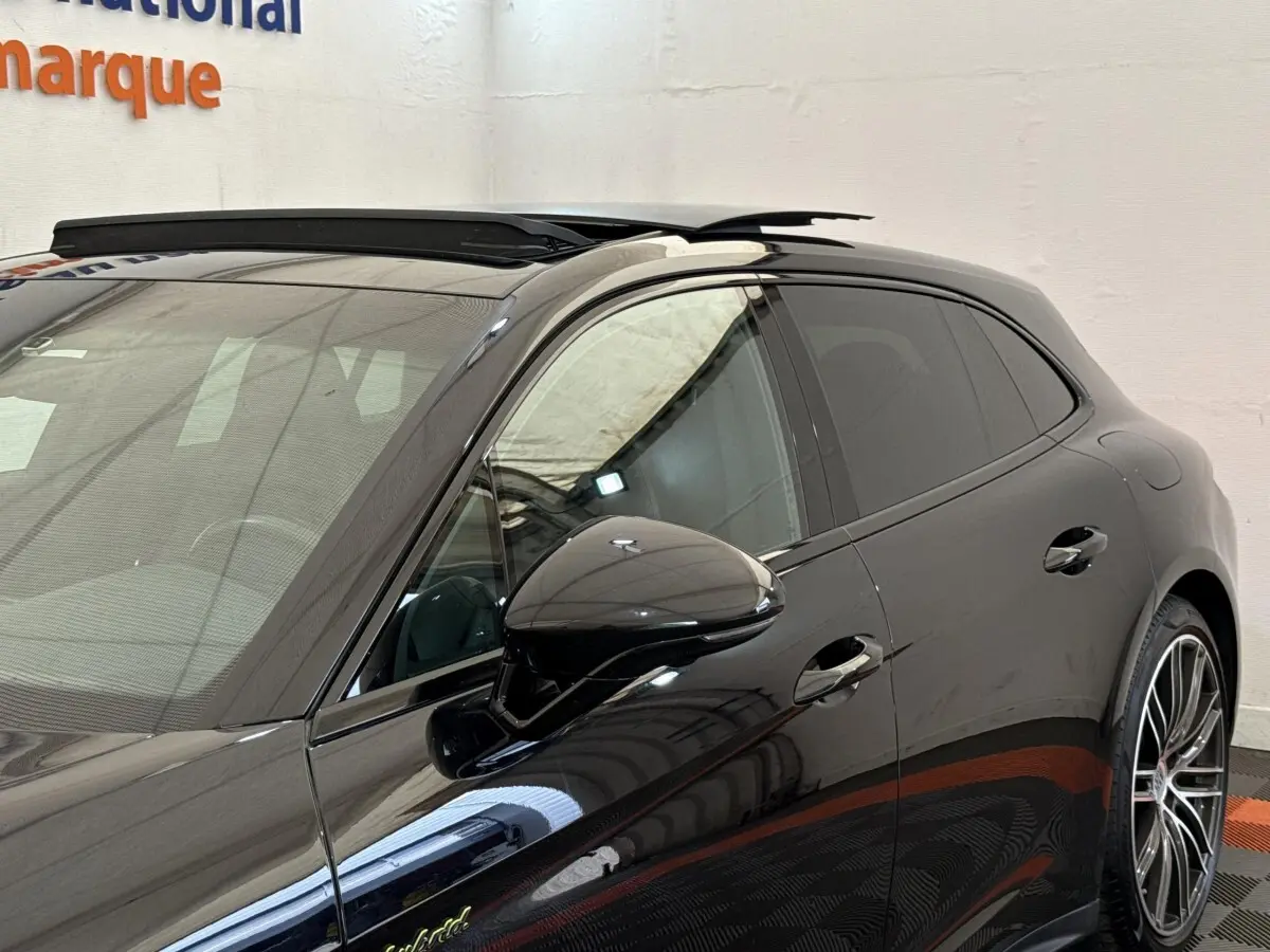 Vue de côté droit avant d'une Porsche Panamera 4 E-Hybrid Sport Turismo noire avec rétroviseur et jante alliage visibles.