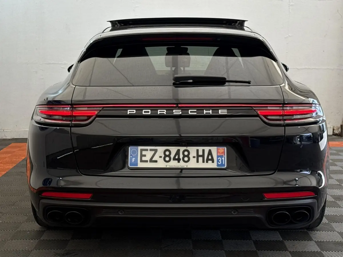 Vue arrière d'une Porsche Panamera 4 E-Hybrid Sport Turismo noire, avec feux LED et double sortie d'échappement.