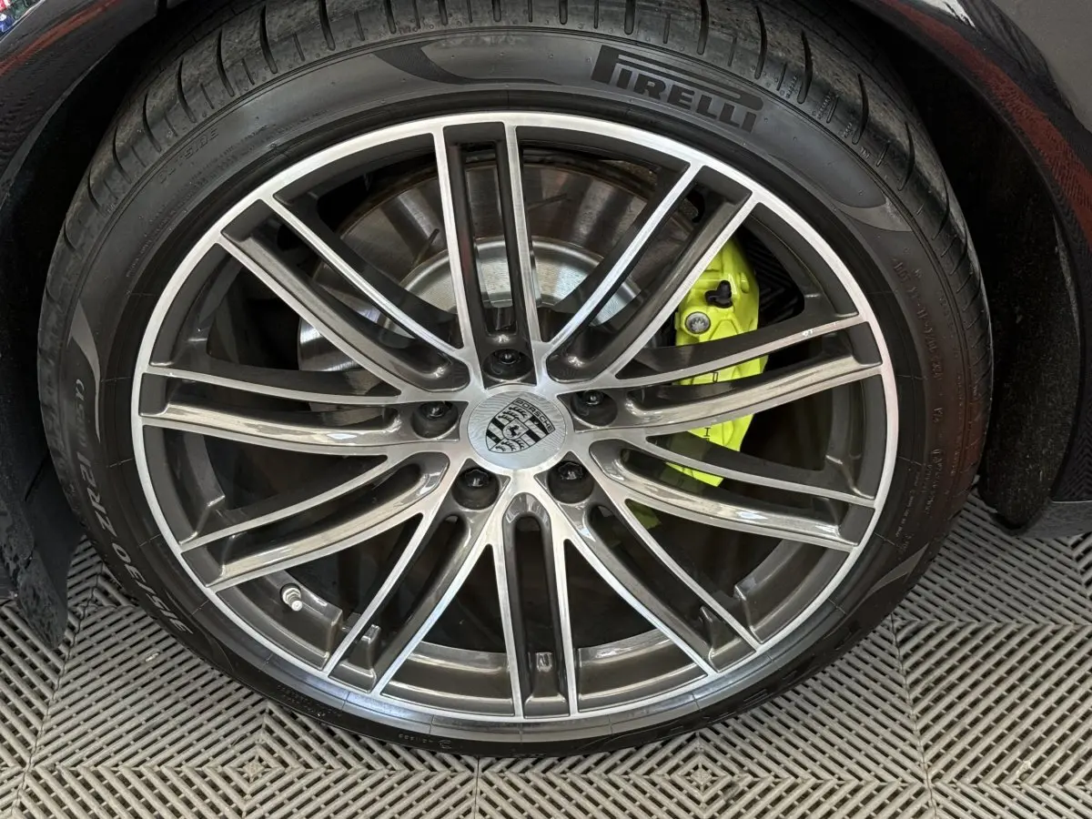 Gros plan sur la roue avant droite d'une Porsche Panamera 4 E-Hybrid noire avec étrier de frein jaune vif.