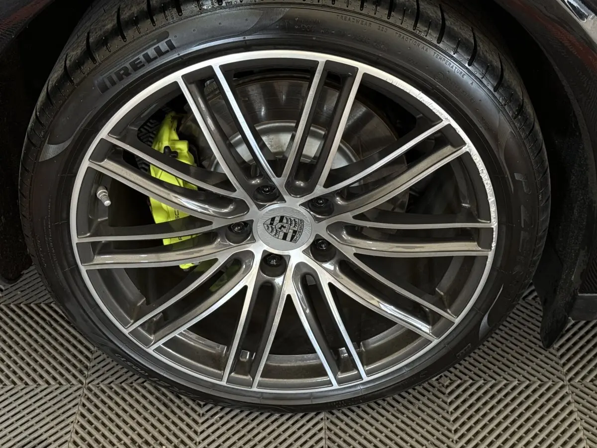 Gros plan sur la jante alliage grise et le frein jaune vif d'une Porsche Panamera 4 E-Hybrid Sport Turismo noire.