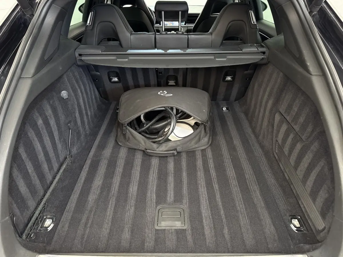 Vue du coffre arrière noir de la Porsche Panamera 4 E-Hybrid Sport Turismo avec sac de câble de recharge au centre.