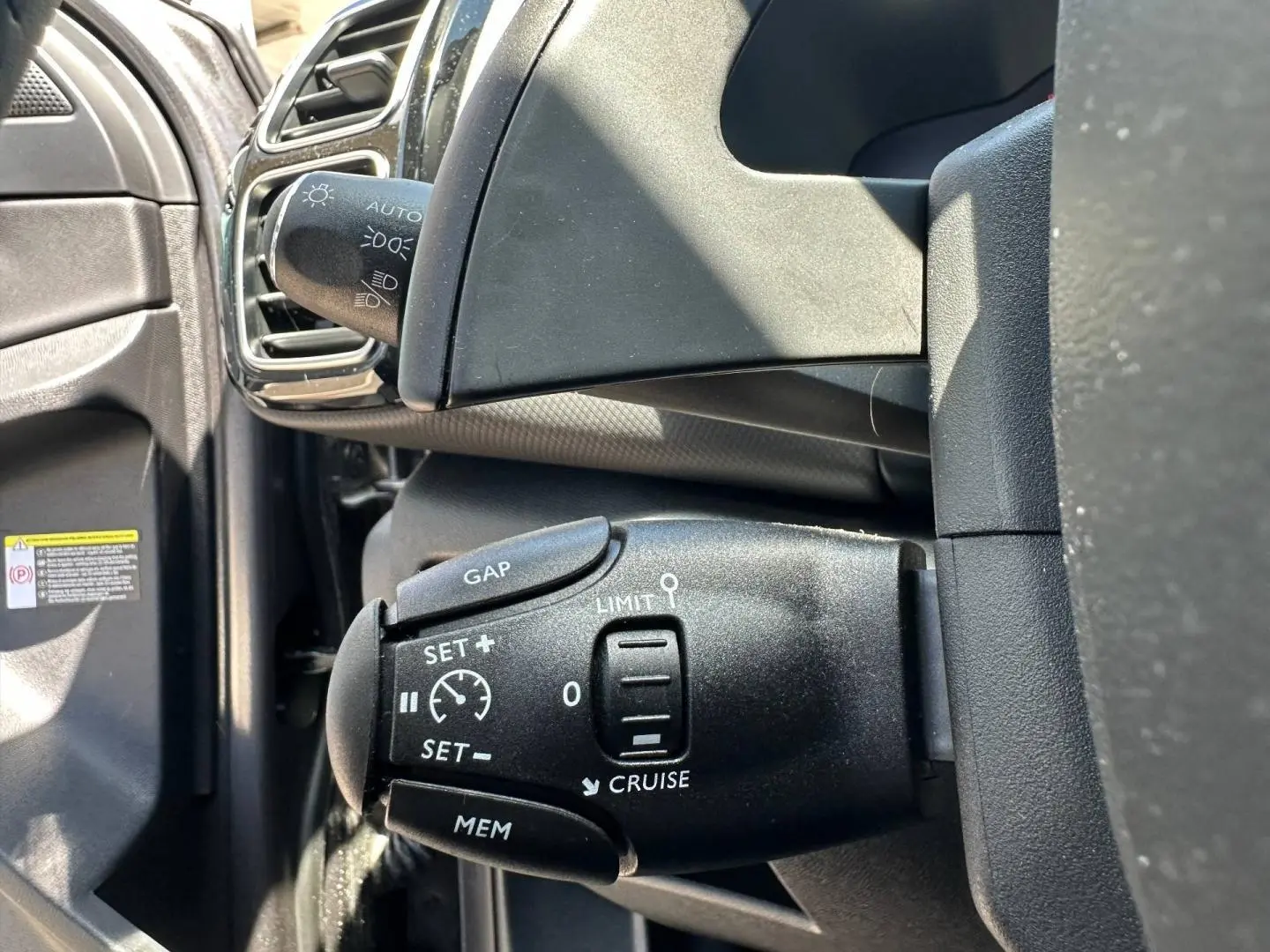 Gros plan sur la commande de régulateur de vitesse à gauche du volant dans un Citroën C5 Aircross gris Platinium.