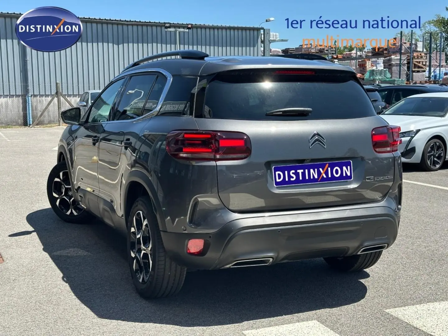Vue 3/4 arrière droite d'un Citroën C5 Aircross gris Platinium avec feux arrière LED et jantes alu noires.