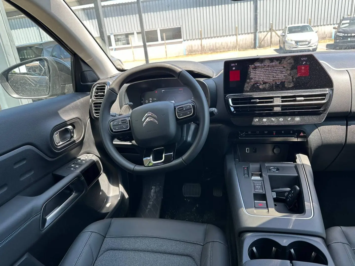 Vue intérieure côté conducteur du Citroën C5 Aircross 2025, volant cuir multifonction et écran tactile central visible.