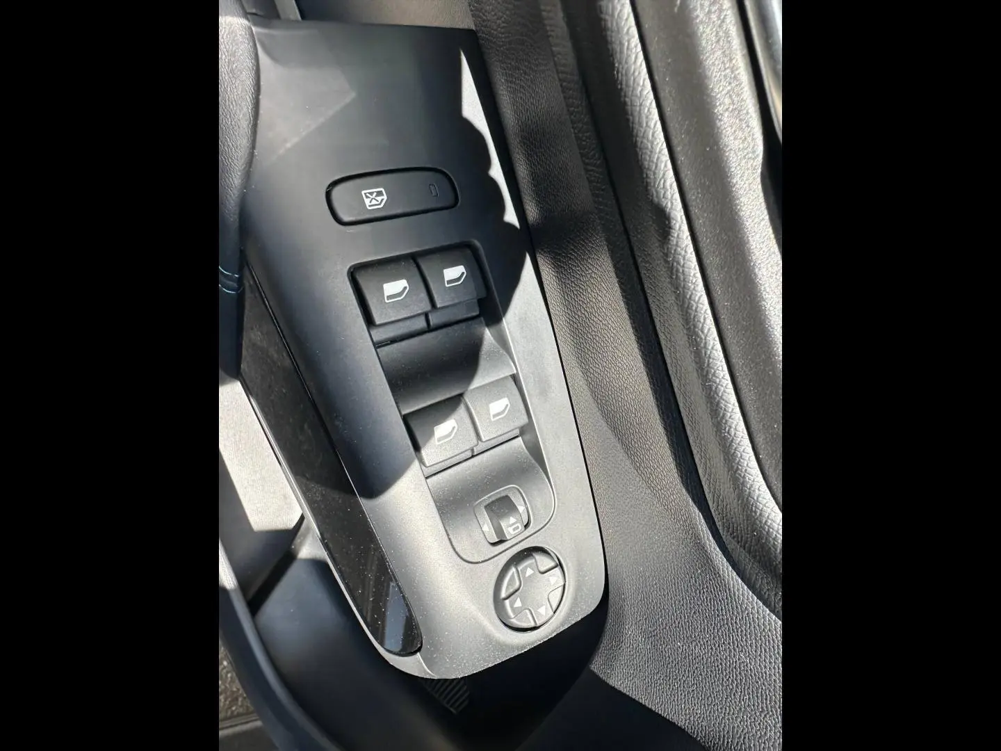 Gros plan sur les commandes de lève-vitres et rétroviseurs côté conducteur du Citroën C5 Aircross 2025 en intérieur noir.