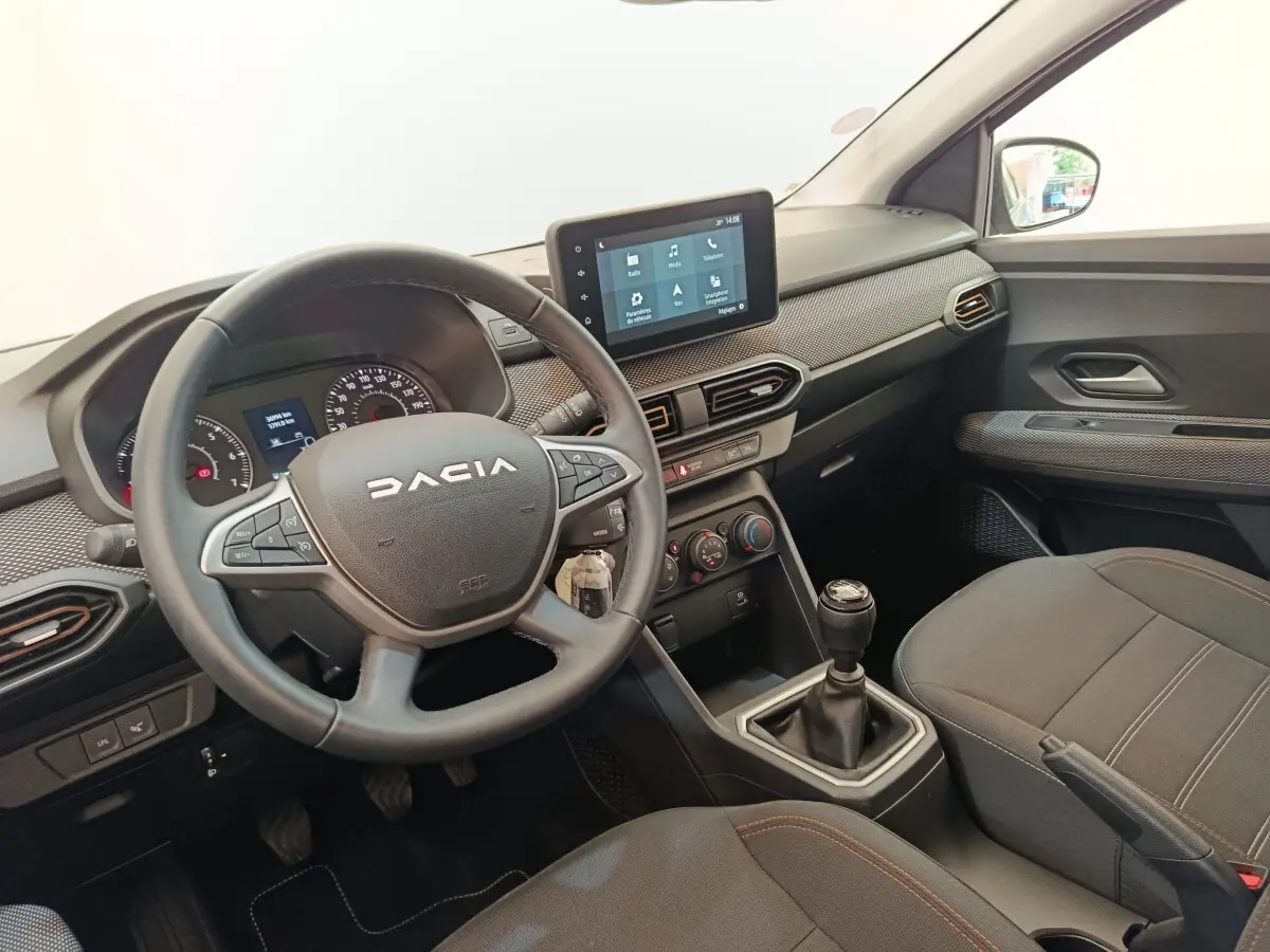 Vue intérieure côté conducteur de la Dacia Sandero Expression EGO-G 100 2023, volant cuir, écran tactile 8 pouces et boîte manuelle.