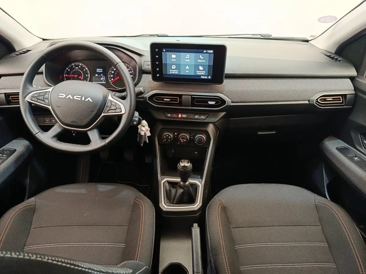 Vue intérieure frontale du tableau de bord et volant cuir synthétique de la Dacia Sandero gris clair 2023 avec écran tactile central.
