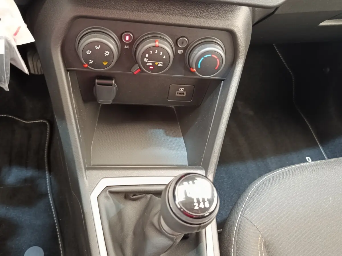 Gros plan sur la console centrale intérieure de la Dacia Sandero 2023, avec levier de vitesse manuel et commandes de climatisation.