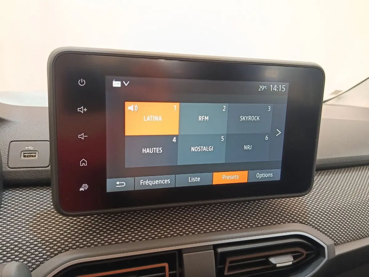Écran tactile central du tableau de bord de la Dacia Sandero gris clair, affichant les stations radio en mode presets.