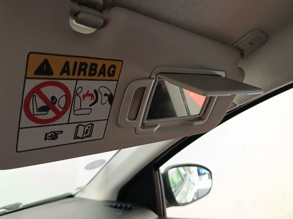 Détail du pare-soleil côté conducteur avec miroir de courtoisie ouvert dans une Dacia Sandero gris clair 2023.