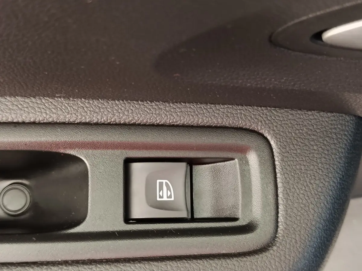 Bouton de commande de lève-vitre électrique sur porte intérieure d’une Dacia Sandero gris clair, version 2023.