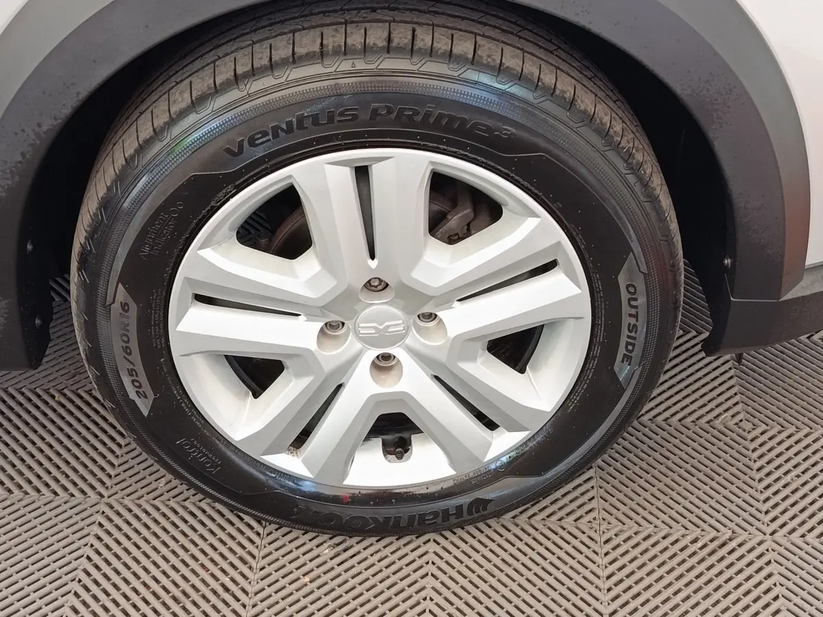 Gros plan sur la roue avant droite d'une Dacia Sandero gris clair, mettant en valeur la jante et le pneu Hankook.