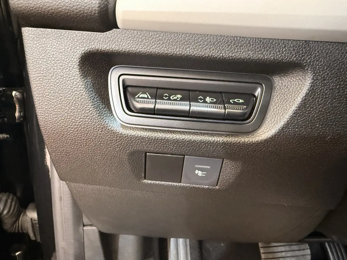 Gros plan sur les commandes noires situées sous le tableau de bord côté conducteur de la Renault ZOE noire 2024.