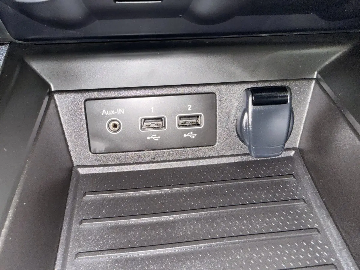 Gros plan sur les prises USB, Aux-IN et prise 12V dans le rangement avant de la Renault ZOE noire 2024.