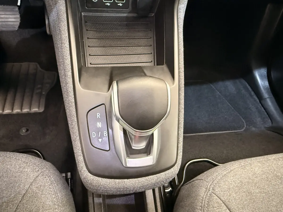 Gros plan sur la console centrale de la Renault ZOE noire 2024, montrant le levier de vitesses automatique et les sièges gris.