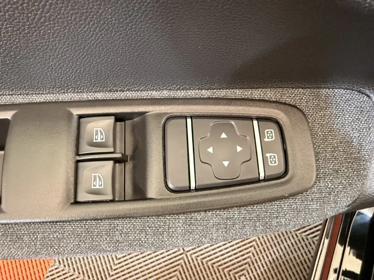 Gros plan sur les commandes de réglage des vitres et des rétroviseurs côté conducteur de la Renault ZOE noire 2024.