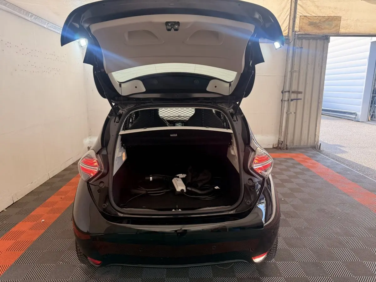 Vue arrière d'une Renault ZOE noire 2024 avec coffre ouvert et câble de charge visible à l'intérieur.