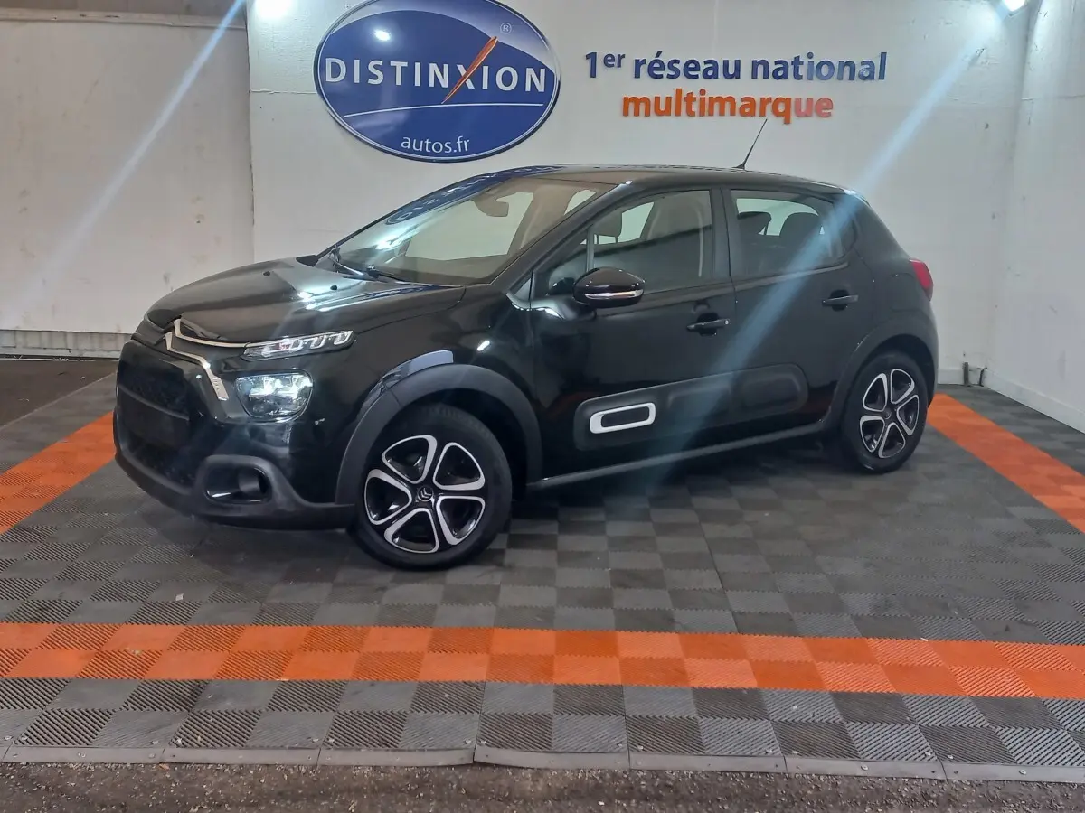 Citroën C3 BlueHDi 100 BVM PLUS noire vue de profil droit en intérieur avec jantes distinctives et protections latérales.
