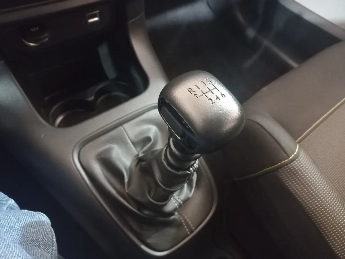Gros plan sur le levier de vitesses manuel noir de la Citroën C3 2024, avec console centrale et siège tissu marron visible.