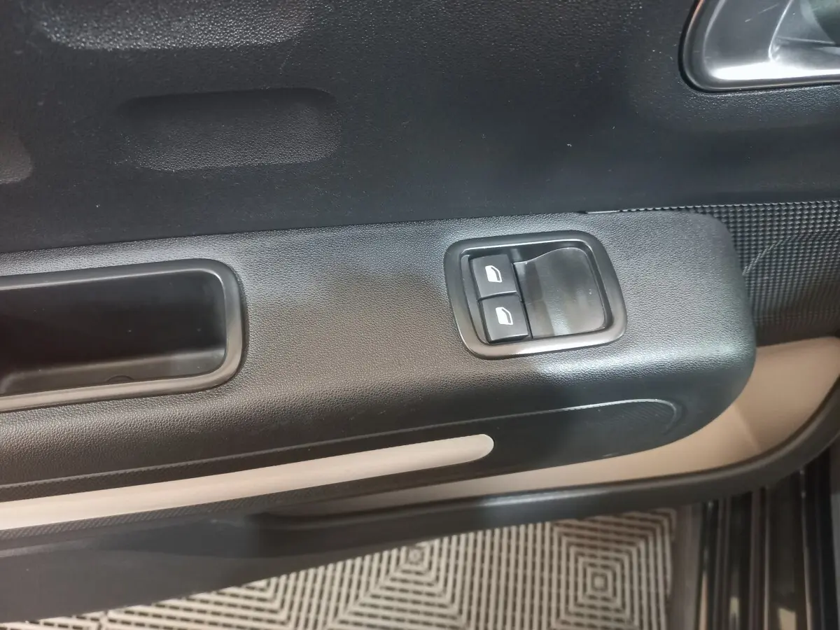 Gros plan sur la commande des vitres électriques côté conducteur de la porte noire intérieure d'une Citroën C3 2024.