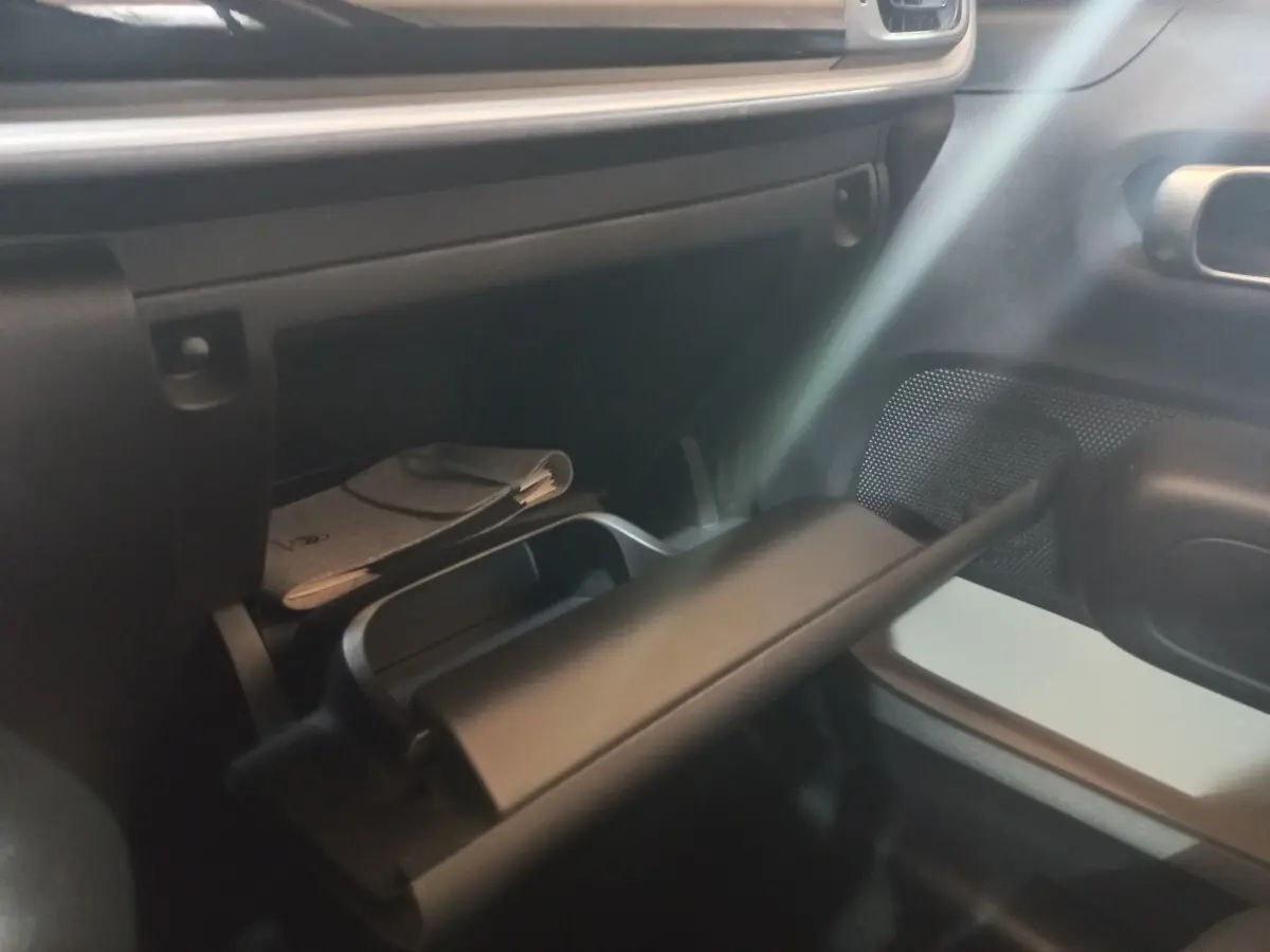Intérieur de la Citroën C3 2024, vue sur la boîte à gants ouverte côté passager avec rangement et documents visibles.