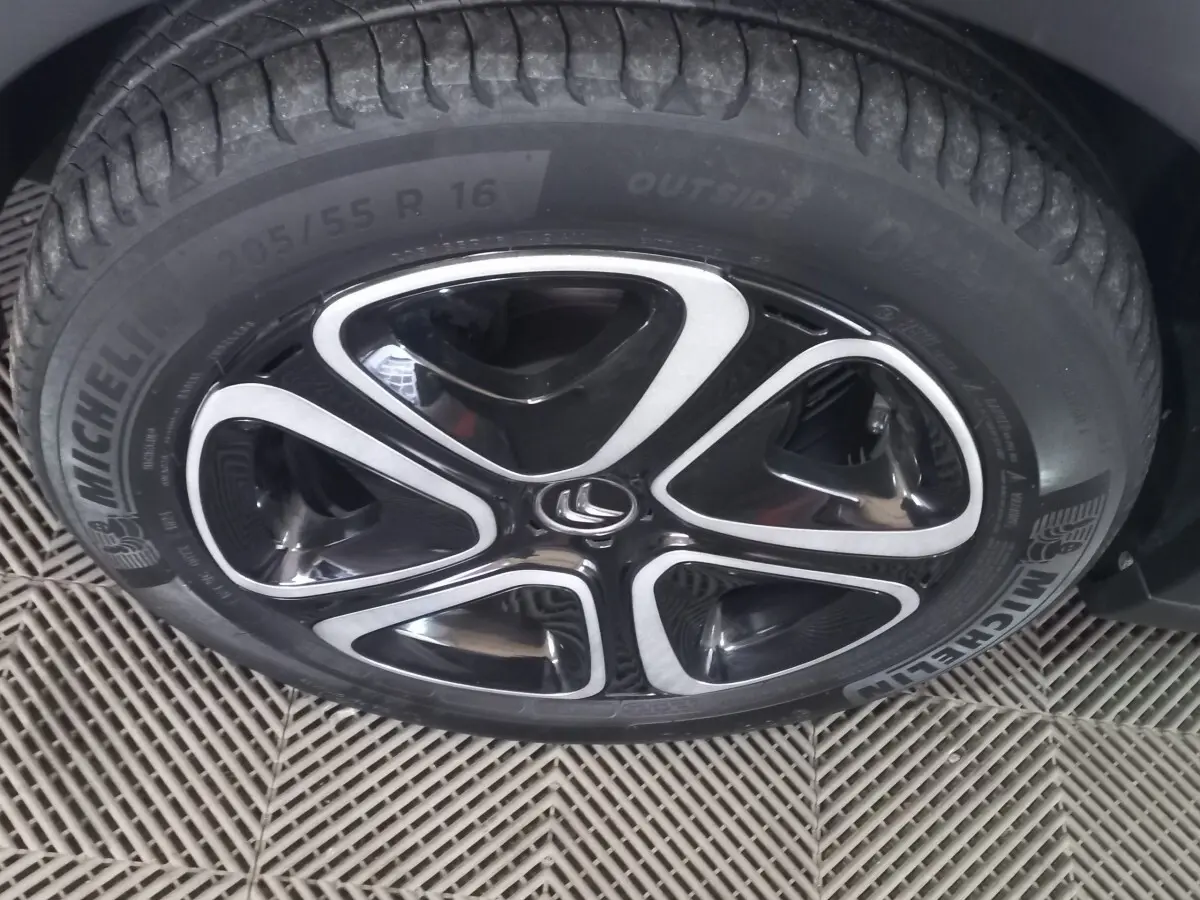 Gros plan sur la roue avant gauche d'une Citroën C3 noire 2024 avec jante alliage noire et argentée distinctive.