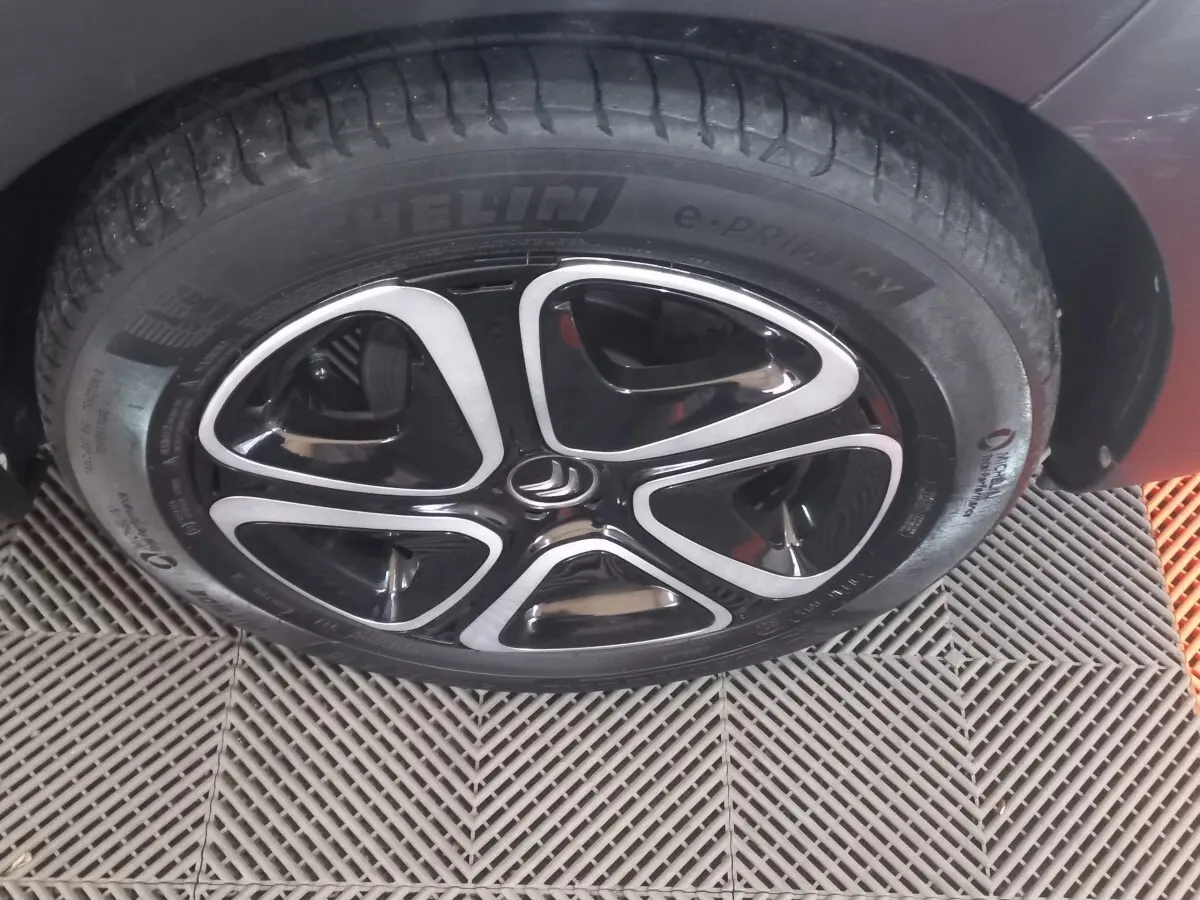 Gros plan sur la roue avant droite noire d'une Citroën C3 2024 avec jante alliage au design moderne bicolore.