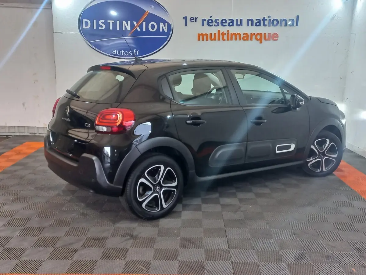 Citroën C3 noire vue en 3/4 arrière droit, avec protections latérales blanches et jantes distinctives.